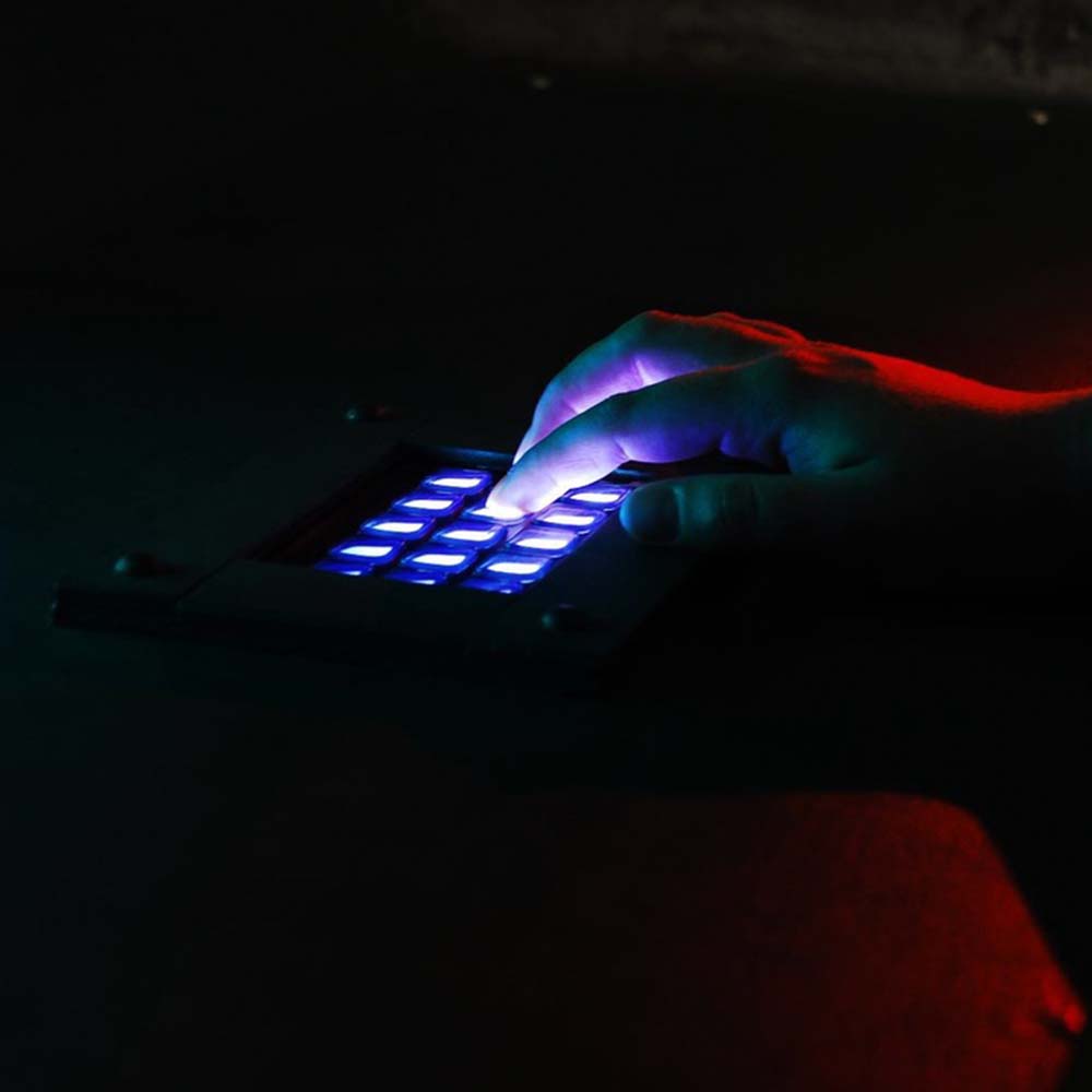 A player's hand pressing an interactive keyboard as part of a puzzle which is lighting up their hand in a mysterious way